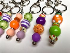 several different colored beads are hanging from key chains on a white surface with silver rings