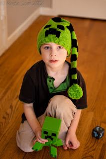 a young boy sitting on the floor wearing a green hat and holding a lego block