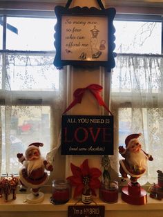 christmas decorations are displayed on a window sill in front of a sign that says, all you need is love