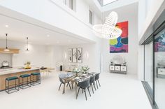 a dining room and kitchen area in a modern home with white walls, flooring and high ceilings