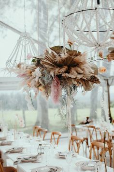 an arrangement of flowers and feathers decorates the center piece of this wedding reception table