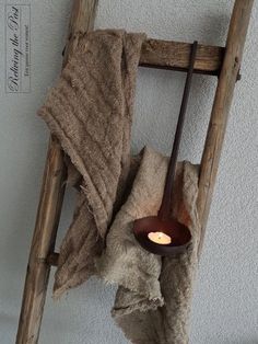 an old wooden ladder with a candle on it and towels hanging from the side,