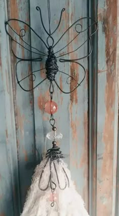 a small white dress hanging from a metal hook on a wooden door with an iron frame