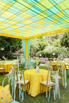 an outdoor wedding venue with yellow and blue tables set up for the guests to eat