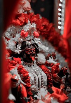 a close up of a statue with red and white flowers on it's head