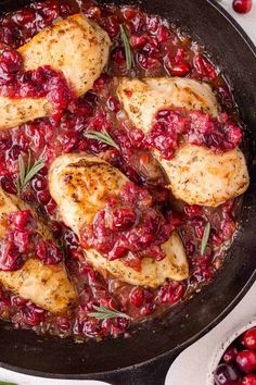 chicken with cranberry sauce in a cast iron skillet surrounded by fresh cranberries