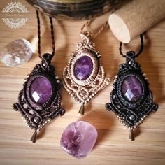 three necklaces with amethyst stones on top of a wooden table next to a roll of paper