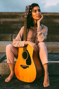 a woman sitting on steps with her guitar