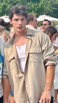 a young man is walking in front of a group of people at an outdoor event