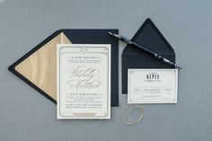 the wedding stationery is laid out on top of the black and gold envelopes