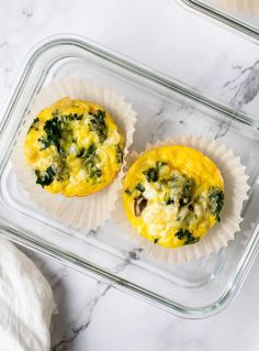 two muffins with cheese and broccoli in them on a marble surface