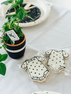 some cookies are sitting on a table near a potted plant and plates with plants in them