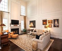 a living room filled with lots of furniture and paintings on the wall next to a fire place