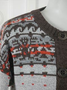 This European vintage cardigan features two shades of gray and brown and rusty orange Fair Isle pattern on the upper front and back, around the waistband, and on the sleeve edges. The handsome sweater has a ribbed crew neckline, ribbed button line, ribbed sleeve cuffs, and a ribbed waistband. The sweater closes in the front with six large brown pearlized buttons. Size: 36 to 38 US/UK Material: Cotton ---MEASUREMENTS--- Chest = 38 inches (96.52cm) Shoulders = 17 inches (43.18cm) Sleeve Length = 2 Brown Sweater For Layering With Button Closure, Orange Buttoned Winter Cardigan, Orange Winter Cardigan With Buttons, Winter Orange Cardigan With Buttons, Cozy Brown Cardigan With Fair Isle Pattern, Cozy Brown Fair Isle Pattern Cardigan, Brown Fair Isle Pattern Winter Cardigan, Vintage Knit Cardigan, Rusty Orange