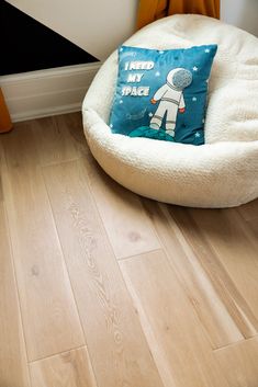 a dog bed with a pillow on top of it in front of a wall and floor