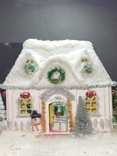 a small white house covered in snow and christmas decorations