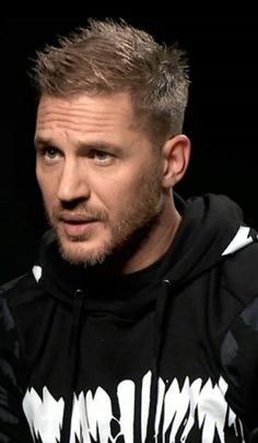 a man wearing a black and white hoodie looking at the camera with an intense look on his face