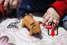 a small brown dog sitting on top of a bed next to a baby's hand