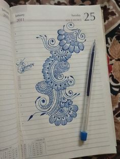 a notebook with an intricate design and a pen sitting on the page next to it