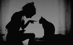 a black and white photo of a woman pointing at a cat