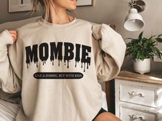 a woman wearing a sweatshirt with the word mombie printed on it