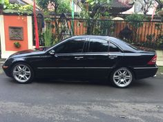 a black car parked on the street in front of a fence and gated area