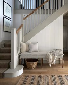 a white bench sitting under a stair case