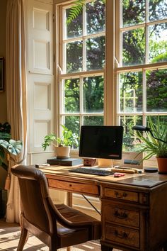 a desk with a computer on top of it in front of a window filled with potted plants