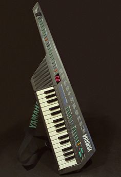 an electronic keyboard sitting on top of a black surface with the words happy written on it