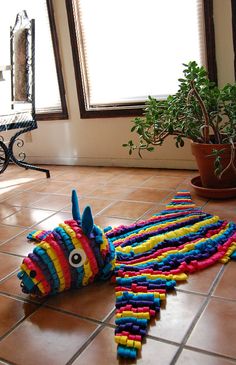 a very cute looking toy laying on the floor in front of a potted plant