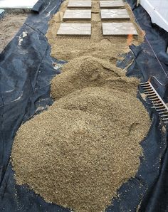 a pile of sand sitting on top of a tarp covered ground next to a building