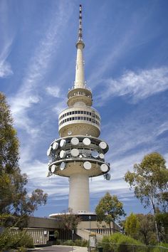 a very tall tower with many lights on it's sides and trees in the background