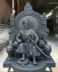 a statue of a man sitting on top of a chair with an animal next to him