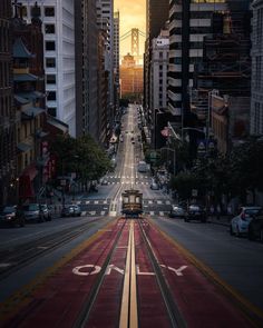 an empty city street is shown with buildings and train tracks on the road in the foreground