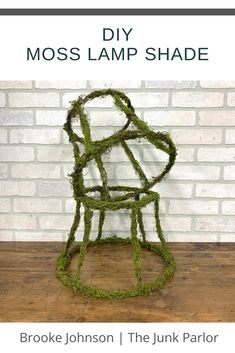 a sculpture made out of moss sitting on top of a wooden table next to a brick wall