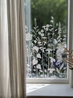 a window with flowers drawn on it and a plant next to the window sill