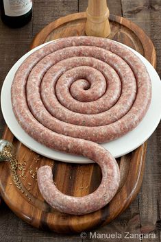 sausage on a cutting board next to a bottle of wine