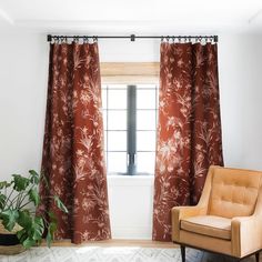 an orange chair sitting in front of a window next to a potted green plant