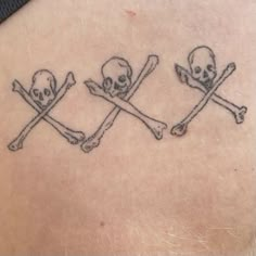 three skulls and crossbones on the back of a woman's shoulder, both with crossed bones