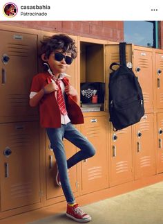 a young boy wearing sunglasses leaning on lockers with his hand in his pocket and holding a backpack