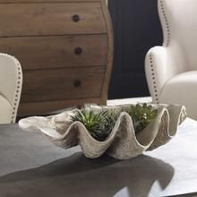 two white chairs sitting next to each other near a table with plants on it and a dresser in the background