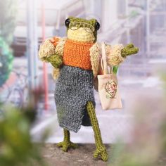 a stuffed frog holding a bag and wearing glasses