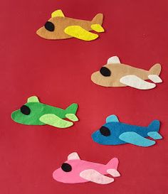 four different colored felt airplanes on a red surface