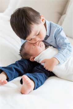 two young boys are laying on a bed and one is kissing the other's face