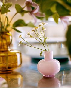 three vases filled with flowers sitting on top of a glass table next to each other