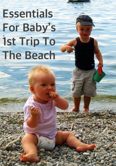 two young children are sitting on the rocks by the water and one is holding something in his mouth