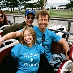 three people wearing sydney in sydney t - shirts posing for a photo at an amusement park