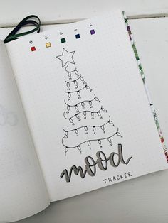 an open notebook with a christmas tree drawn on the cover and words mood tracker written in cursive writing