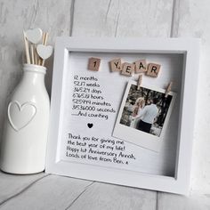 a photo frame with the words 1 year on it next to a vase and toothpicks