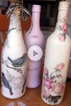 three painted bottles sitting on top of a wooden table